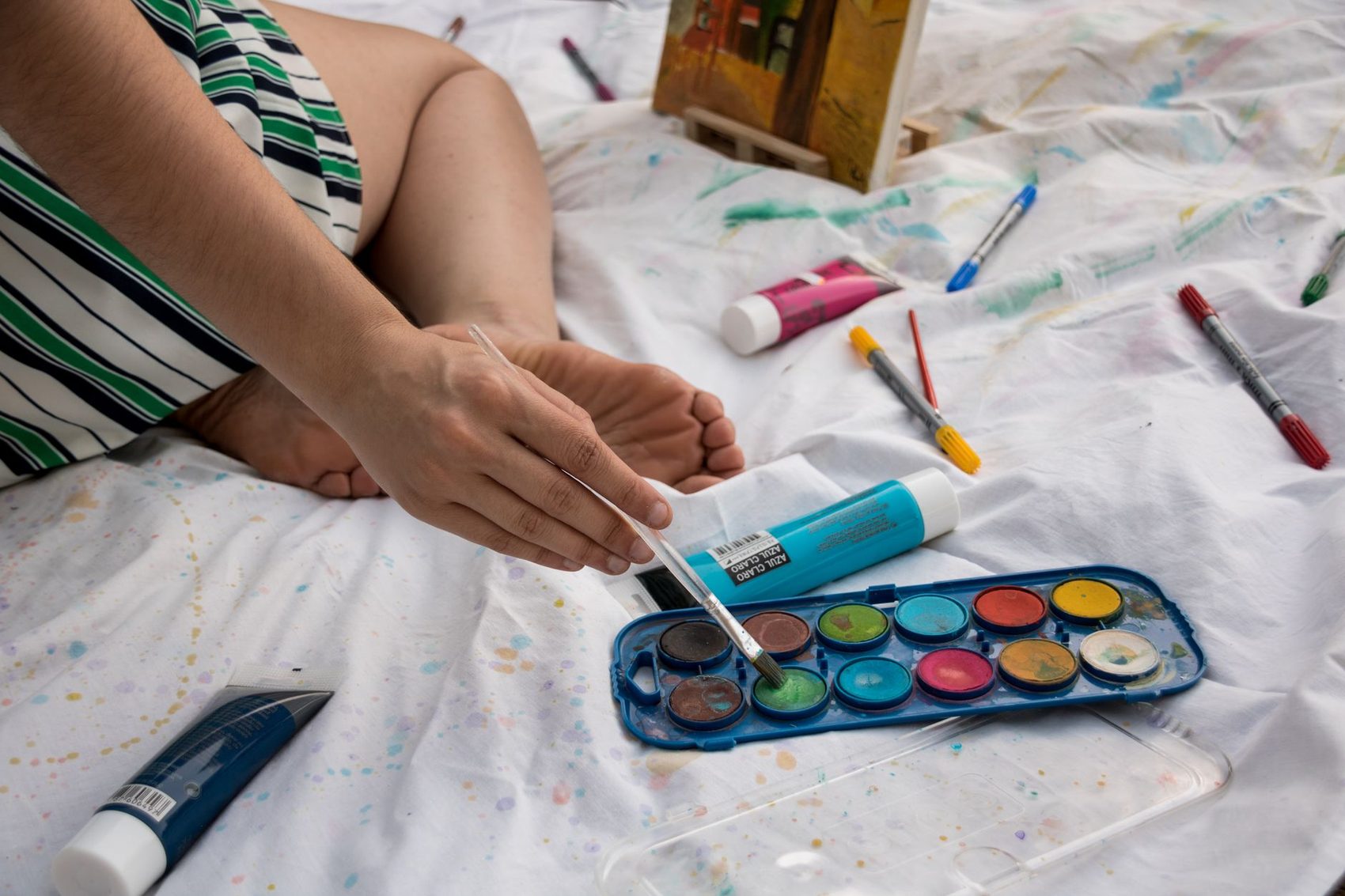 Materiales de arte terapia: acuarelas y pinceles sobre una mesa de trabajo cálida